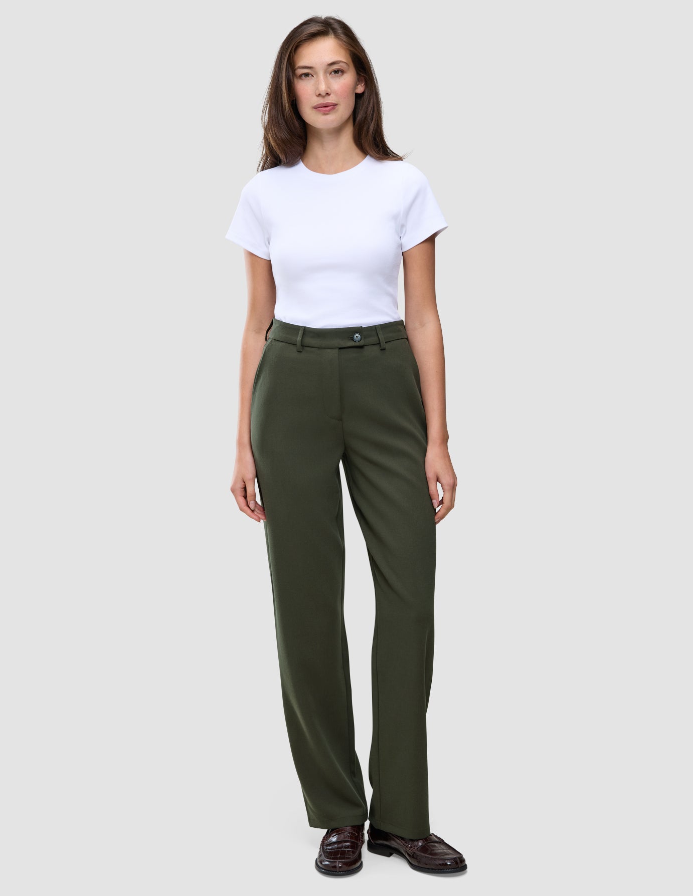 A woman wearing a white t-shirt and Women GO2 Pants Straight Dusty Olive, featuring a high-waisted, straight-leg fit.